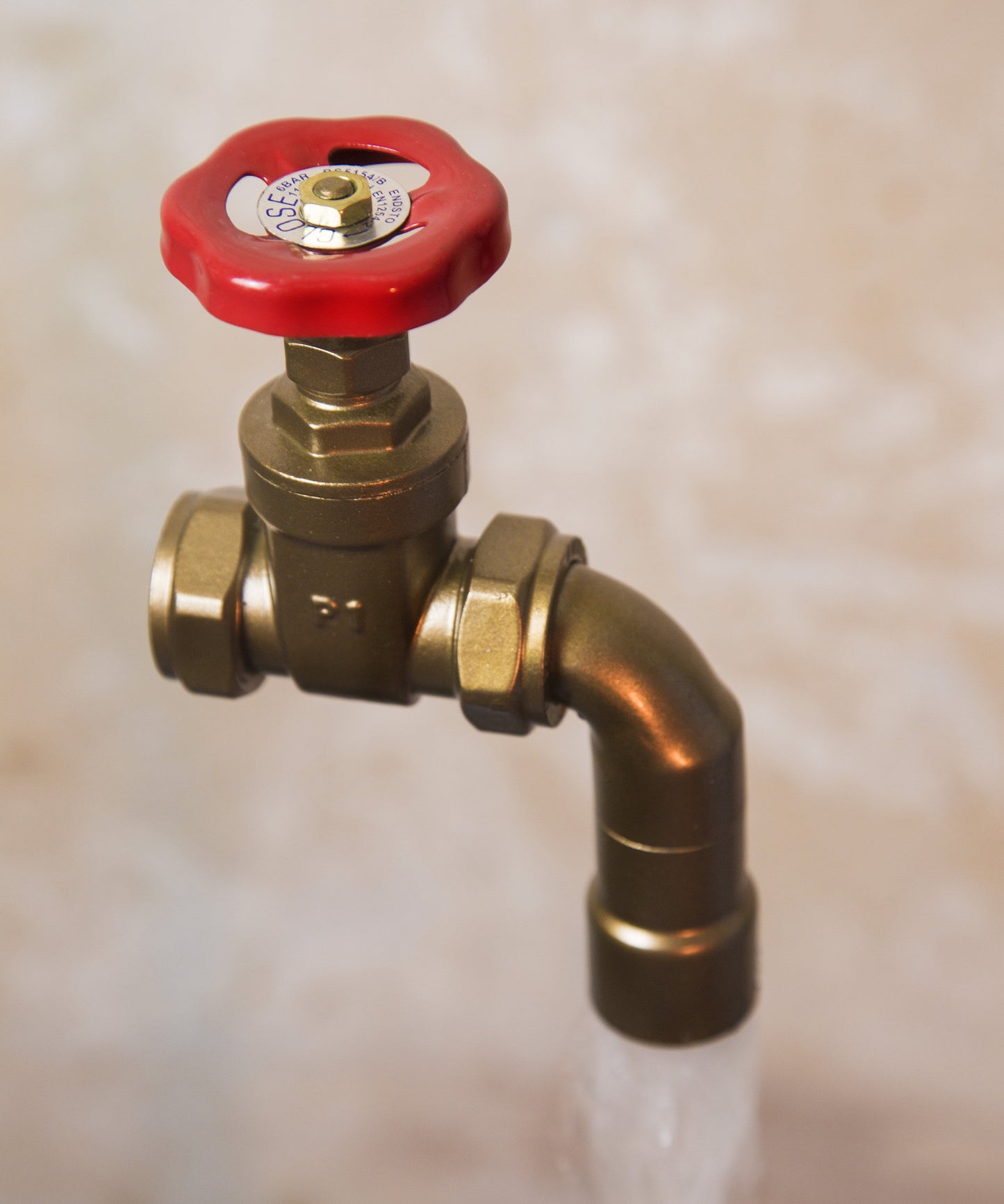 A floating tap water feature with a red gate valve tap with water flowing into the magically set in a industrial business environment.