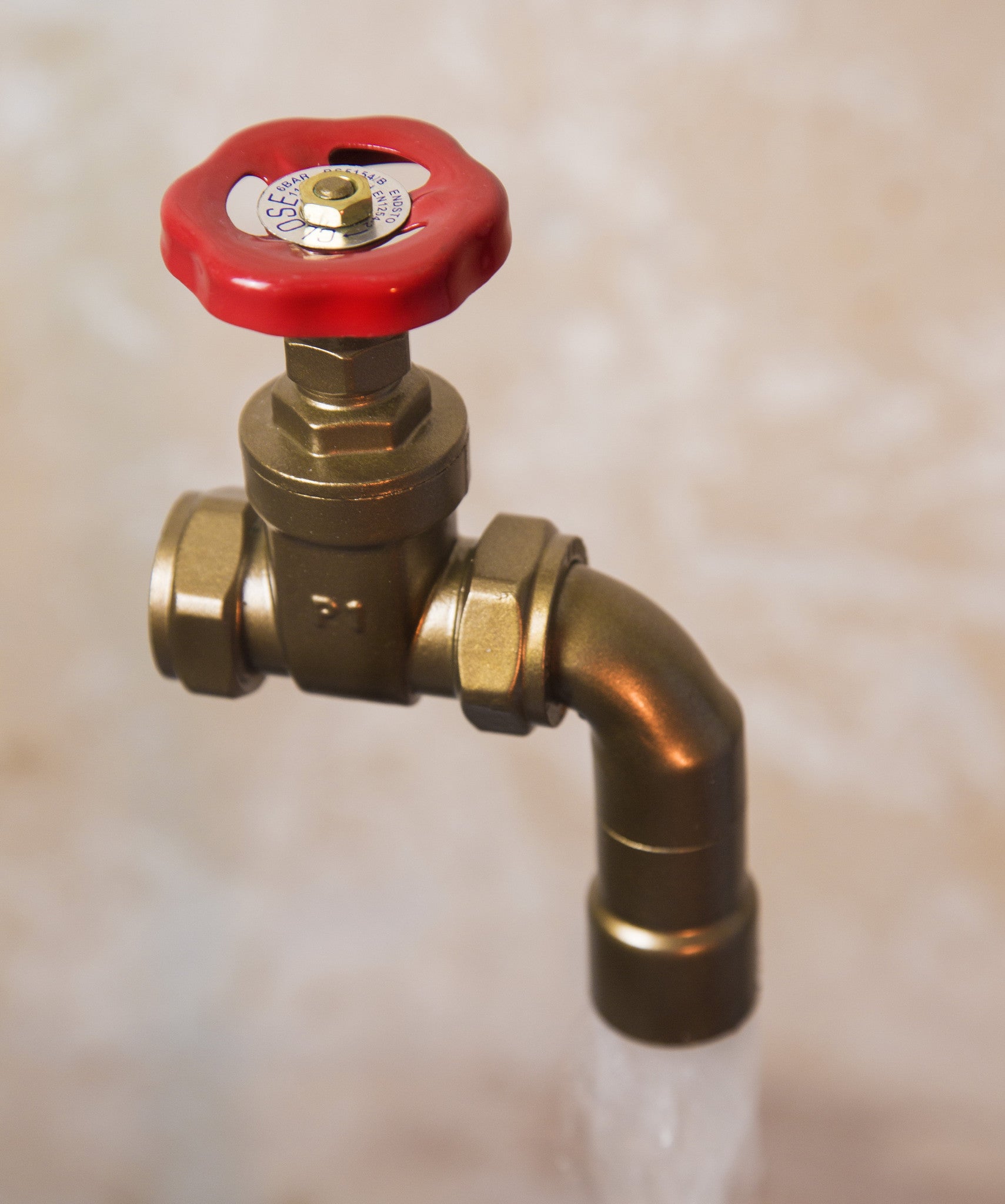 A floating tap water feature with a red gate valve tap with water flowing into the magically set in a industrial business environment.
