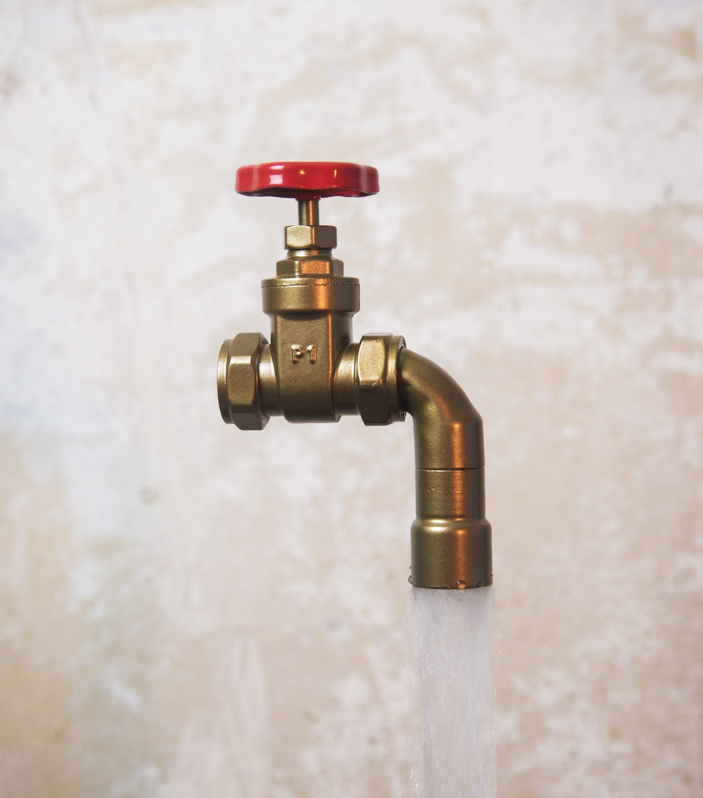 A floating tap water feature with a red gate valve tap with water flowing into the magically set in a industrial business environment.