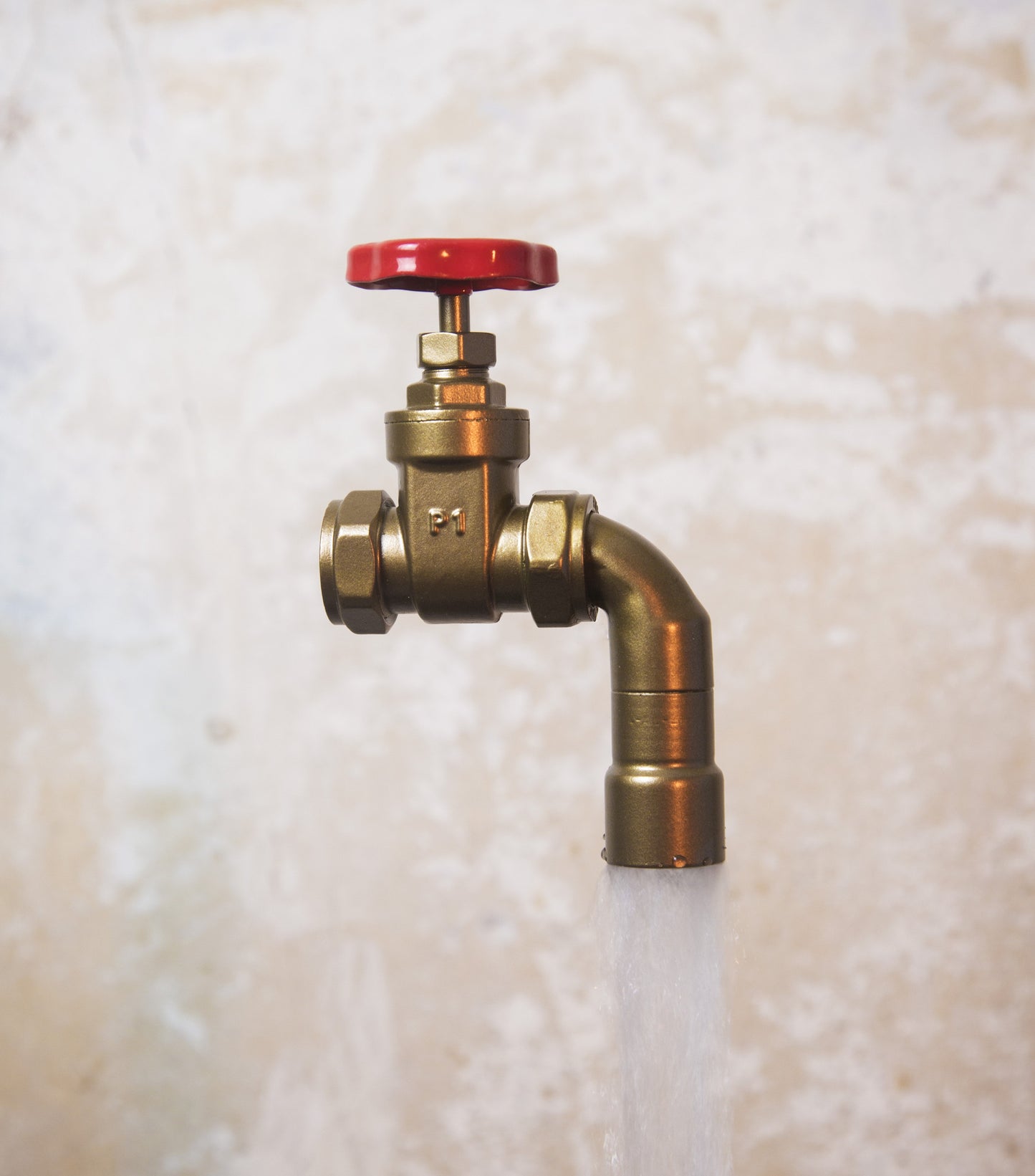 A floating tap water feature with a red gate valve tap with water flowing into the magically set in a industrial business environment.