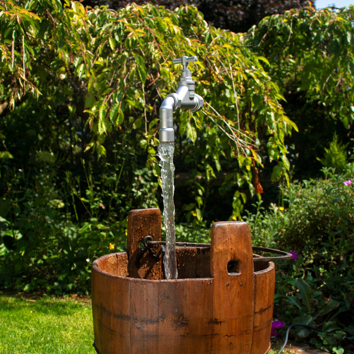 A silver floating tap floating above an antique wooden pail