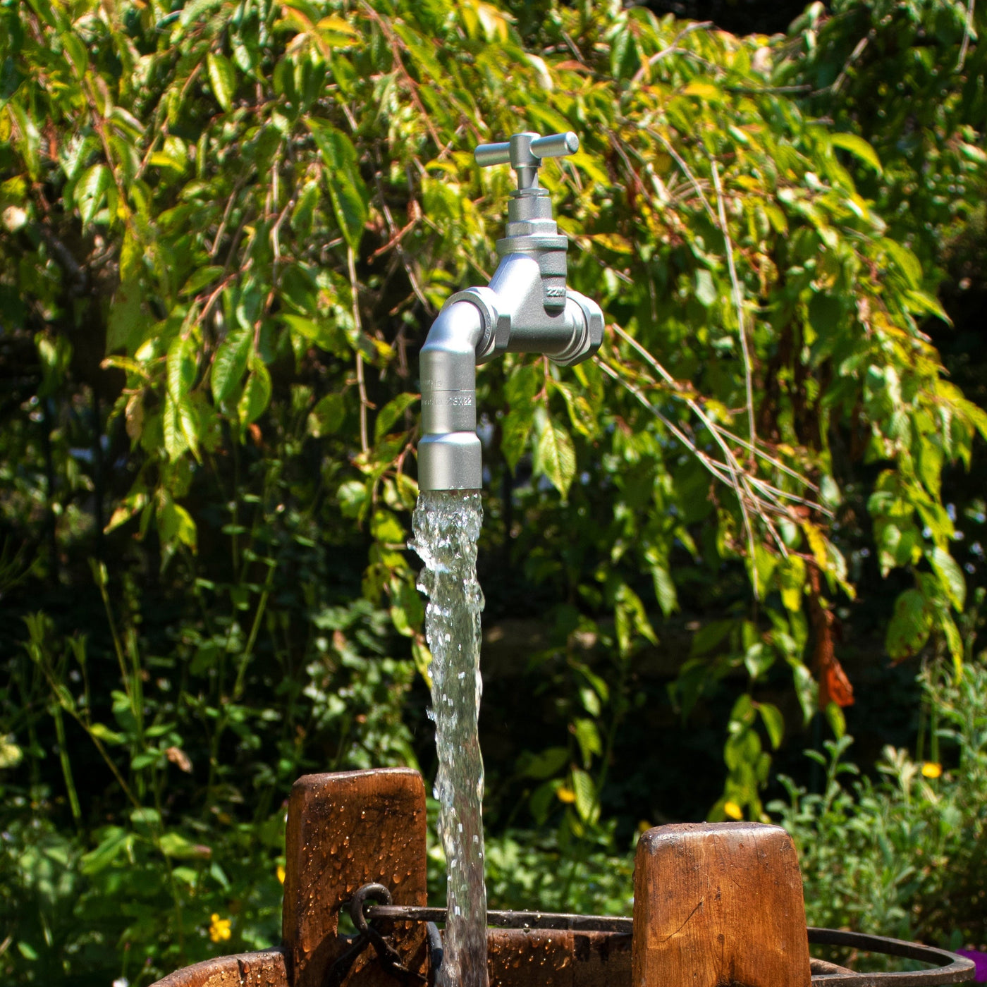 A silver floating tap floating above an antique wooden pail