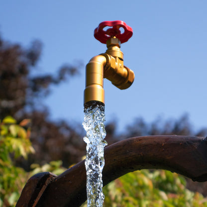 The Wheel Floating Tap Suspended against blue sky with an antique wooden pail handle bucket below